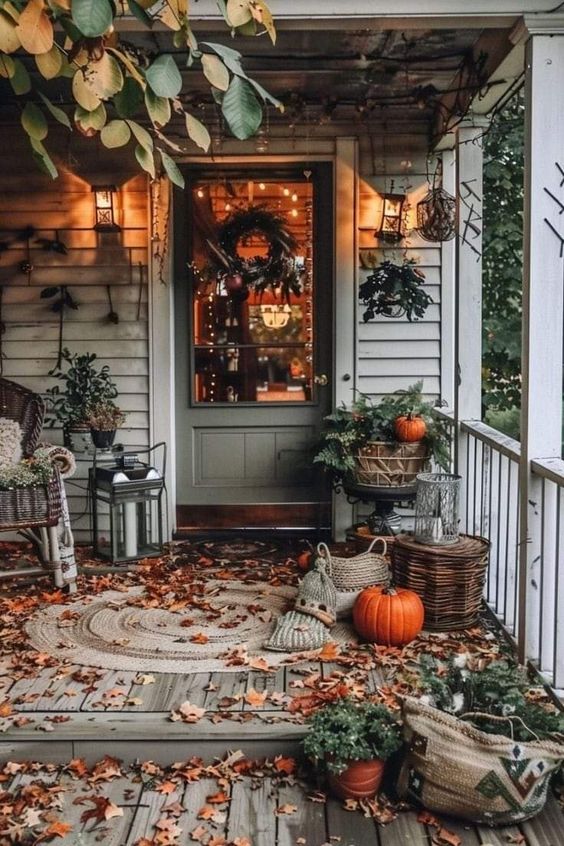 Nothing says 'welcome home' like this charming fall-decorated porch! The weathered wooden boards are sprinkled with autumn leaves, creating a natural carpet of color. A cozy wicker chair with a warm throw invites you to sit and enjoy the crisp air. Pumpkins are tucked into every corner, from the steps to the rustic baskets, adding that perfect touch of seasonal cheer. The soft glow from the lanterns and the wreath on the door make this entrance feel so inviting, it’s like the house is giving you a warm hug!