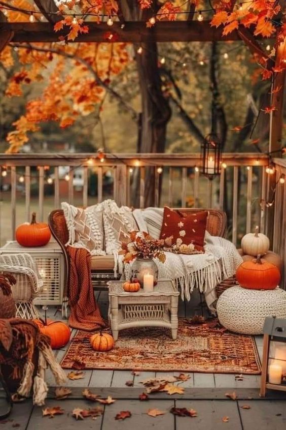 This outdoor space is a dreamy autumn oasis! Nestled under a canopy of golden leaves, the cozy seating area is perfect for enjoying the crisp fall air. The wicker furniture is draped with soft, textured blankets and adorned with pillows in warm, earthy tones, creating an inviting spot to relax. A scattering of pumpkins adds a festive touch, while the twinkling string lights overhead cast a magical glow, turning this deck into a cozy retreat. The combination of rustic elements, like the woven rug and lanterns, with the vibrant colors of fall, makes this space the ultimate outdoor haven for the season.