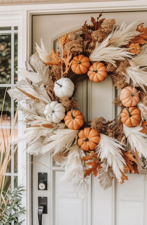 This fall wreath is a stunning blend of natural textures and seasonal charm, making it the perfect adornment for any front door. The wreath features a mix of small orange and white pumpkins, nestled among soft, wispy pampas grass and dried foliage, creating a beautiful contrast of colors and materials. The addition of rich brown and beige tones, along with autumn leaves, adds warmth and depth to the design. This wreath captures the essence of fall with its earthy elegance and festive spirit, welcoming guests with a stylish nod to the season.