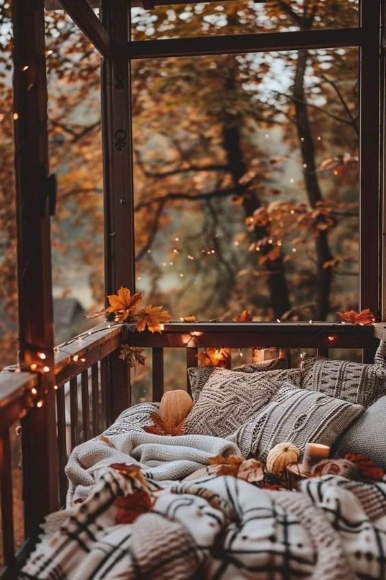 This cozy nook is the perfect autumn retreat! Nestled on a porch or balcony, it’s surrounded by the golden hues of fall foliage. The space is draped with soft blankets and plump pillows, inviting you to snuggle up with a good book or simply enjoy the crisp autumn air. Twinkling string lights add a magical touch, creating a warm and intimate atmosphere as the evening sets in. Scattered leaves and a few small pumpkins are the finishing touches, making this the ultimate spot to relax and soak in the beauty of the season.