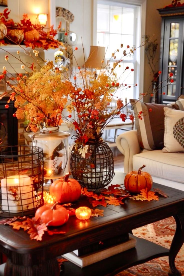 This living room is bursting with autumnal energy! The coffee table takes center stage with a vibrant display of mini pumpkins, glowing candles, and a mix of colorful fall leaves that spill across the dark wood surface. Tall vases filled with branches, berries, and dried florals add height and texture, creating a lively and festive atmosphere. The warm tones of the decor harmonize beautifully with the cozy seating area in the background, making this space feel both inviting and seasonally festive. It’s a perfect setup for enjoying the crisp fall days from the comfort of indoors!