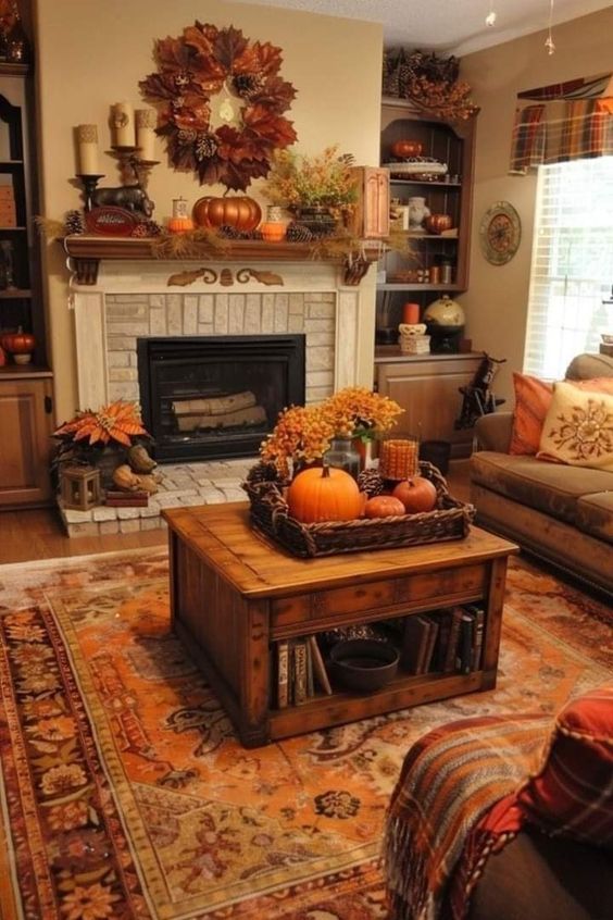 This living room is the perfect embodiment of autumn warmth and comfort. The fireplace, with its brick surround and ornate wooden mantel, is the focal point, adorned with a mix of pumpkins, candles, and fall foliage. Above, a wreath made of autumn leaves adds a seasonal touch, drawing the eye upward. The rich, earthy tones continue throughout the room, from the orange and red accents in the area rug to the cozy plaid throw draped over the armchair. The coffee table is styled with a wicker tray filled with pumpkins, candles, and hydrangeas, creating a beautiful autumnal centerpiece. Shelves and cabinets are thoughtfully decorated with more seasonal touches, making this room feel both festive and inviting, perfect for enjoying the cozy days of fall.