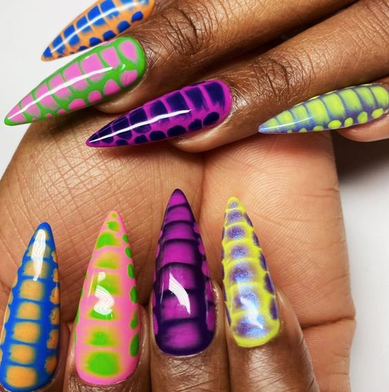 Vibrant and daring, this nail design features a kaleidoscope of colors in a snake skin pattern, blending bright shades like green, pink, blue, purple, and yellow. The glossy finish and stiletto shape add an edgy touch, making these nails a bold fashion statement for anyone who loves to stand out.