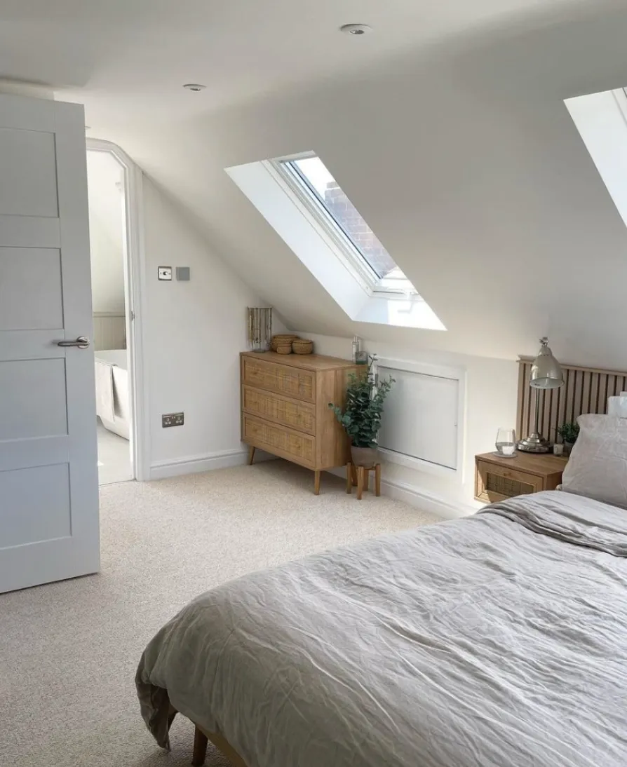 Minimalist EleganceClean lines and neutral tones dominate this attic bedroom, with skylights flooding the space with natural light. The wooden dresser and simple greenery offer warmth, while the understated decor keeps the focus on the bright, airy ambiance.