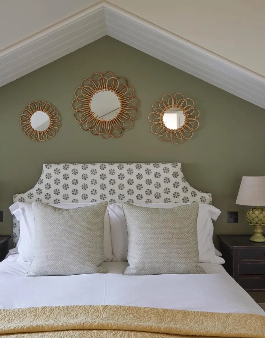 Bold Patterns and PersonalityA vibrant, patterned headboard becomes the focal point in this attic retreat. The mint-green walls and layered gallery wall add personality, while the gold-accented lamps and scalloped furniture give it a polished, designer look.