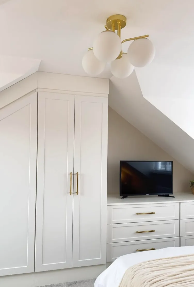 Tailored Storage CharmThis compact attic room maximizes space with custom-built wardrobes and dressers. The golden hardware adds a touch of luxury, while the neutral palette keeps the design timeless and sophisticated.