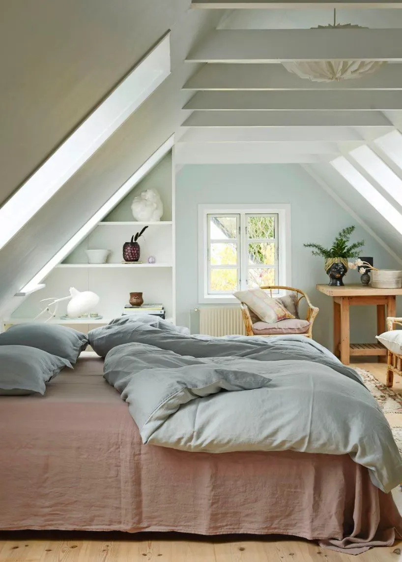 Scandinavian SimplicitySoft pastel walls and built-in shelves define this Scandinavian-inspired attic bedroom. The rattan chair and wooden table create a cozy corner for relaxation, while the airy design ensures a fresh, open feel.