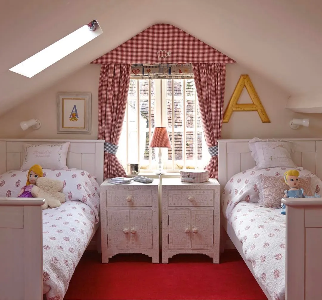 Classic Cottage FeelWith its red gingham curtains and cozy twin beds, this attic bedroom feels like a classic storybook setting. The central window brings in light, while the built-in bedside tables provide a practical solution for small spaces.