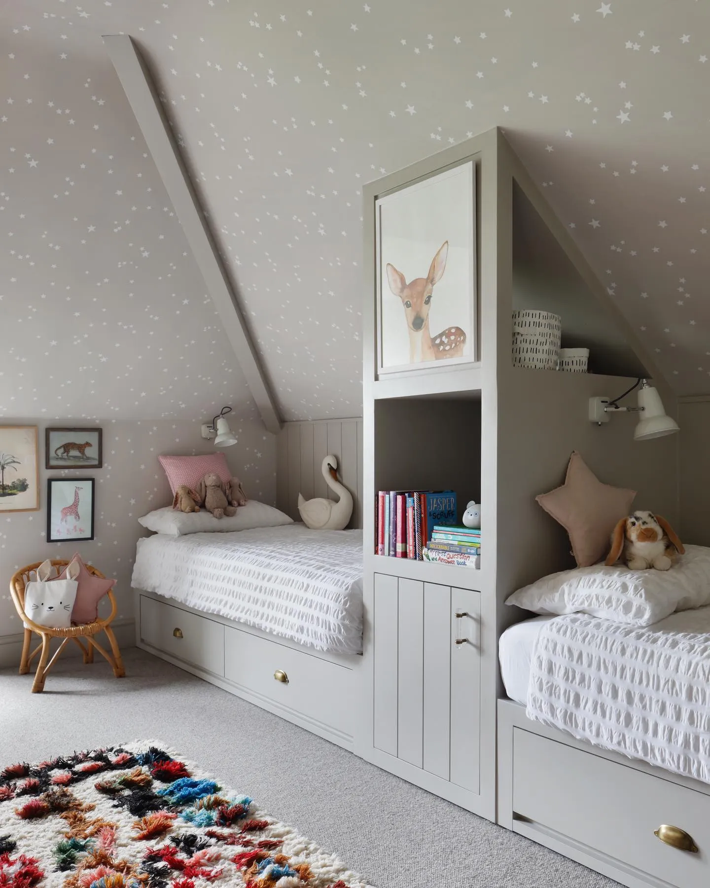 Starry Night MagicThis attic bedroom embraces its sloped ceiling with starry wallpaper that turns the ceiling into a playful feature. Built-in beds with integrated storage are both space-saving and stylish, and the pops of color in the rug add personality to the room.