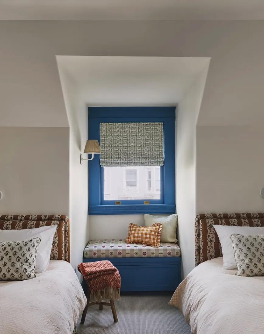 "Pop of Blue" – The vibrant blue window nook and bed frame make this room stand out, while plaid and floral accents add a cozy touch.