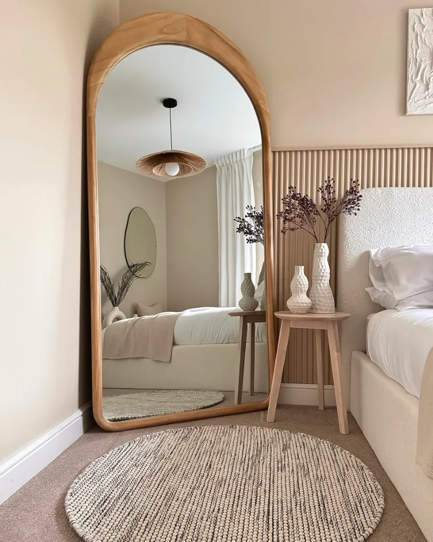 Soft and Serene with an Arched FrameAn arched wooden-framed mirror brings warmth and tranquility to this neutral-toned bedroom. Positioned alongside a cozy woven rug and delicate vases, it’s a perfect way to add character while maintaining a serene vibe. The shape of the mirror softens the room’s overall look, while its placement helps to create the illusion of more space. A freestanding arched mirror like this is easy to incorporate and instantly elevates the room’s decor.