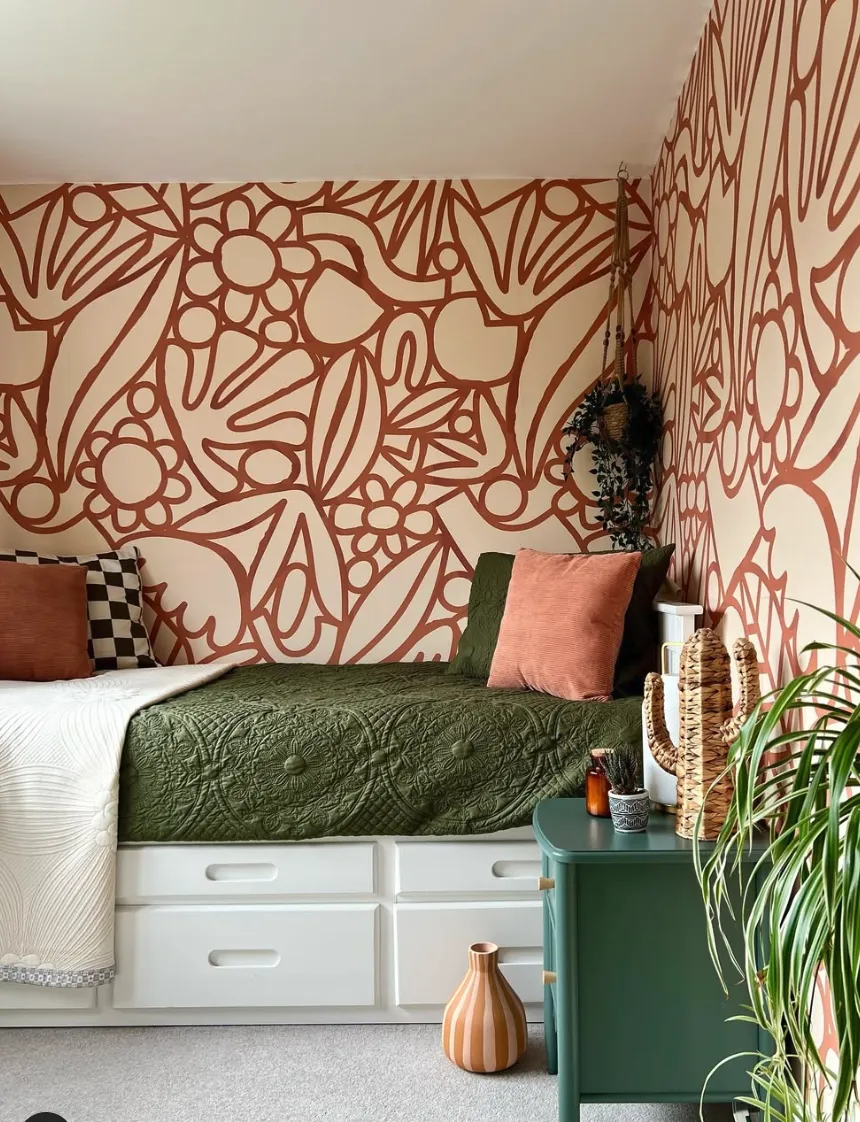 Abstract Botanical Mural in Terracotta Tones This modern, hand-painted mural in terracotta hues adds warmth and character to a cozy bedroom nook. The abstract floral and leaf patterns create an eye-catching backdrop for the earthy green bedding and natural wood accents. DIY enthusiasts can replicate this mural with some masking tape, paint, and creativity, making it a fun weekend project to completely revamp your space.