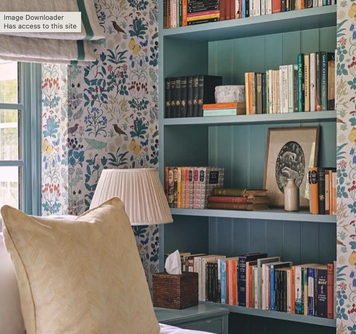 Cozy Nook with Bookshelves: A soft blue built-in shelving unit sits against a backdrop of charming floral wallpaper, blending practicality with aesthetics. It’s the perfect spot for displaying books, decor, and art, adding both character and functionality to the bedroom.