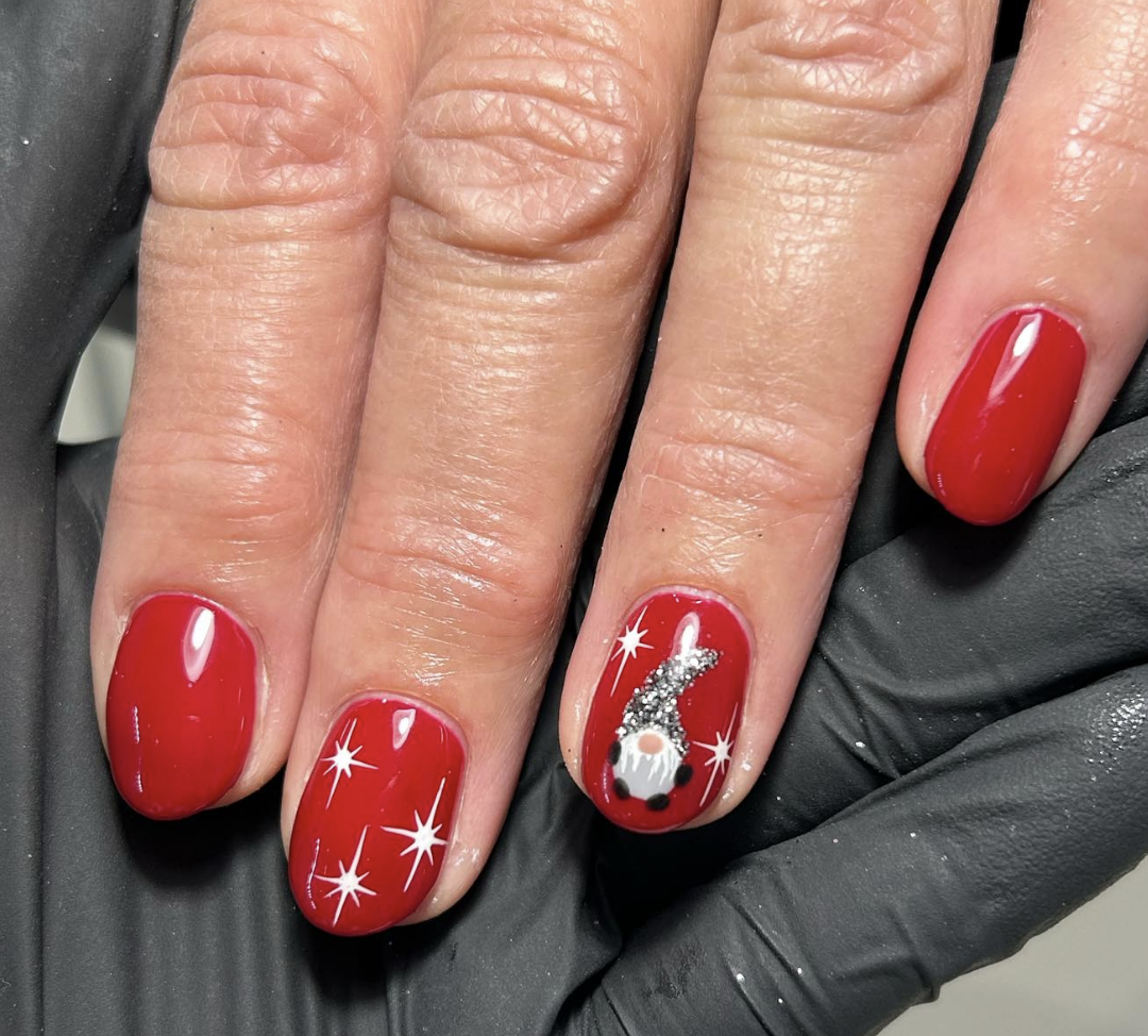 Sparkling Gnome Charm: A simple yet elegant red manicure with an accent nail featuring a silver gnome, adding a touch of holiday sparkle. This design is classy and perfect for both formal and casual gatherings. @mhnails.beauty