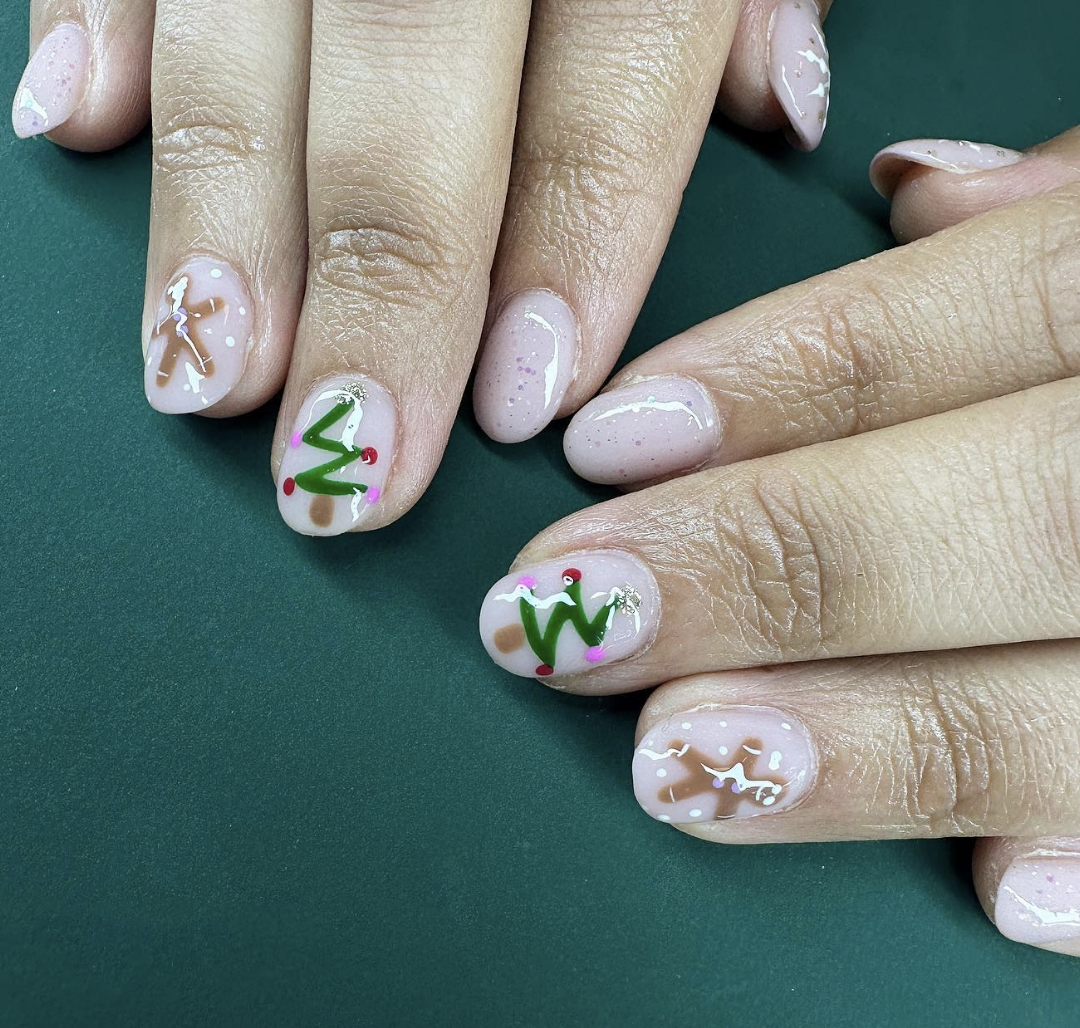 Gingerbread and Trees: These nails feature minimalist gingerbread men and Christmas trees on a nude base, decorated with small pops of red and green. This playful look is both subtle and festive, perfect for understated holiday cheer. @fingerbanginnails