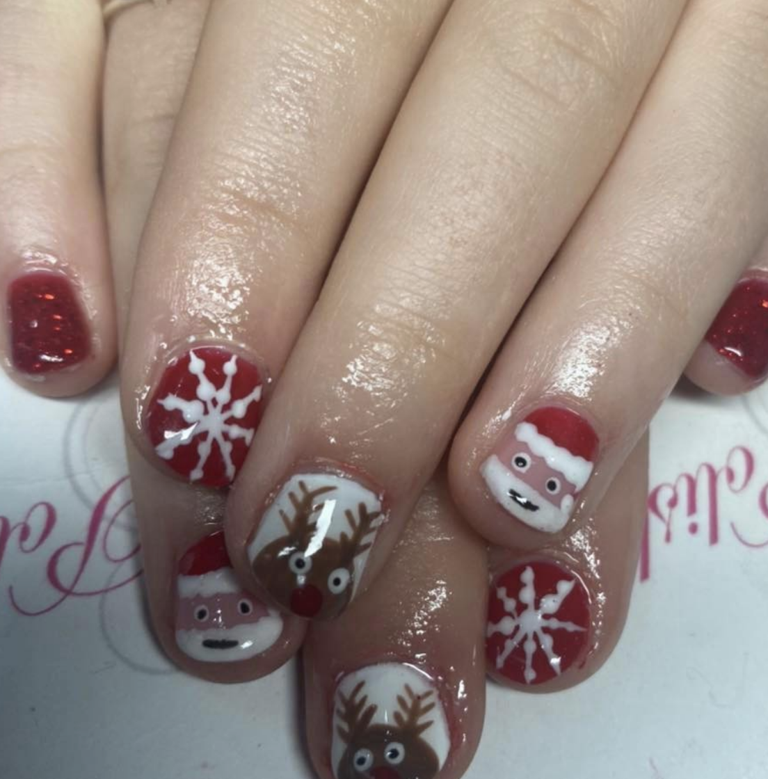 Santa’s Little Helpers: Red and white nails with snowflakes, Santa faces, and reindeer add a playful and cheerful holiday vibe. This design is ideal for anyone looking to bring some Christmas cheer to their nails. @louiseclancy757