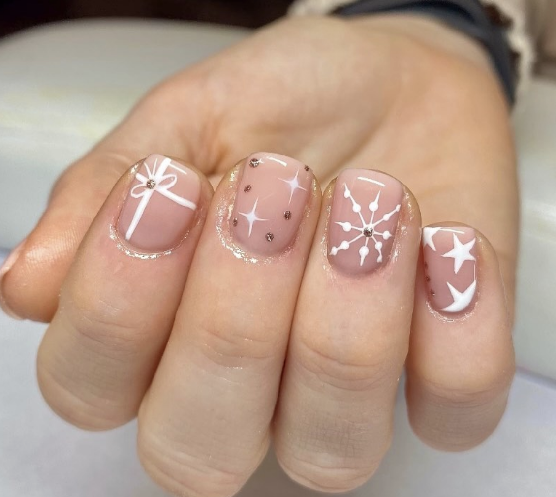 Snowy Gifts: Nude nails with white ribbon details and soft, snowy accents bring an elegant holiday look. This subtle, refined style is great for those who want a hint of festivity. @nailsbyolivialouise