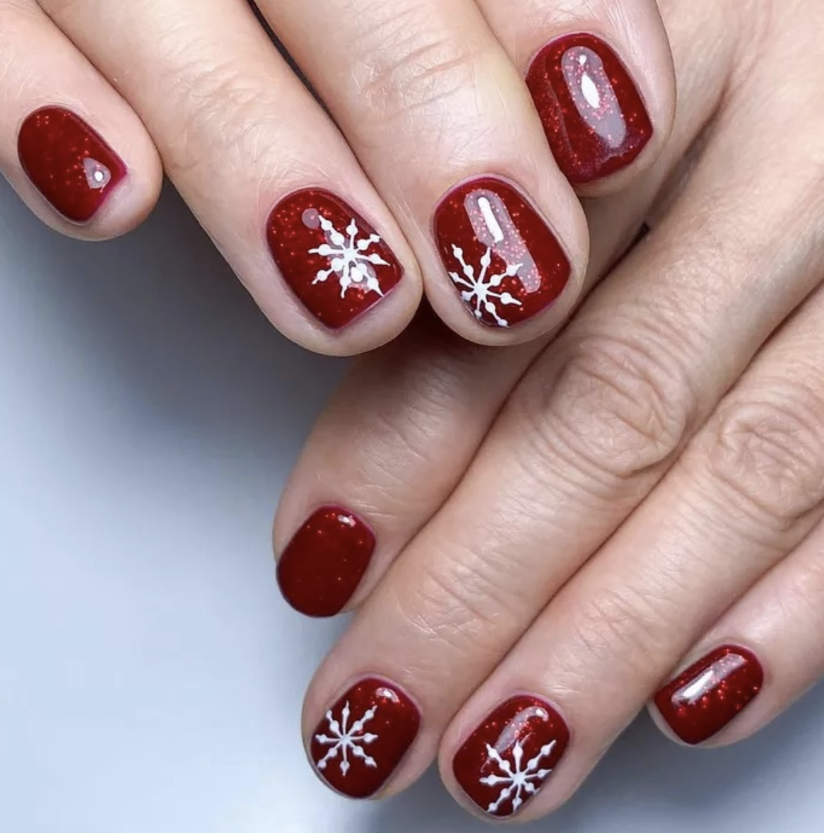 Classic Snowflakes: Deep red nails feature delicate white snowflakes, giving a cozy, wintry vibe. This design brings a traditional yet modern twist that’s ideal for short nails. @bohoblissbali