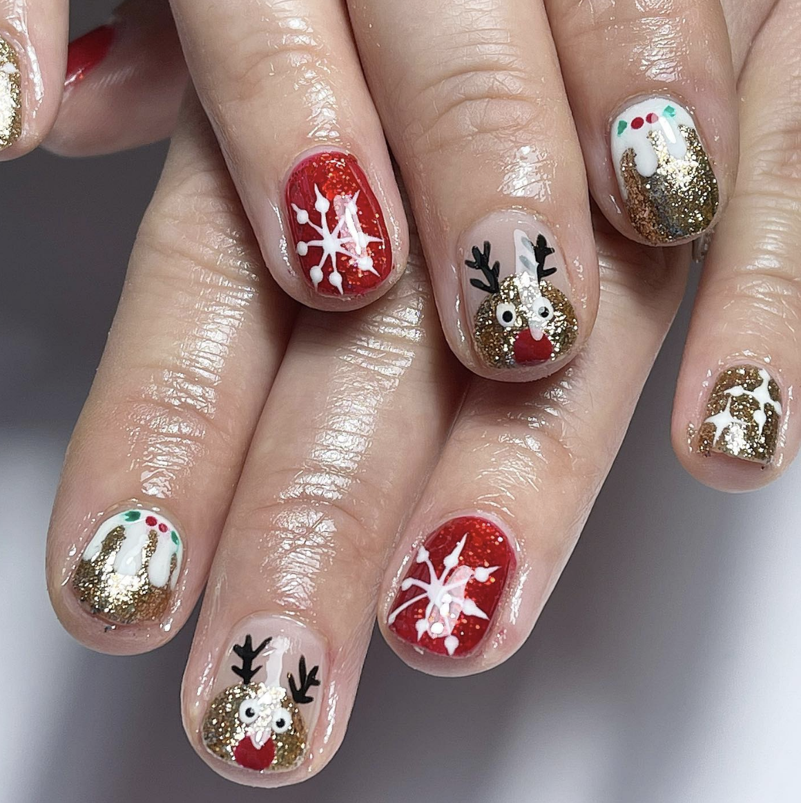 Bold and Bright: Glittery gold and red polish set the stage for reindeer and snowflake designs. These nails are vibrant and full of holiday spirit, perfect for making a statement. @popbeautynorwich