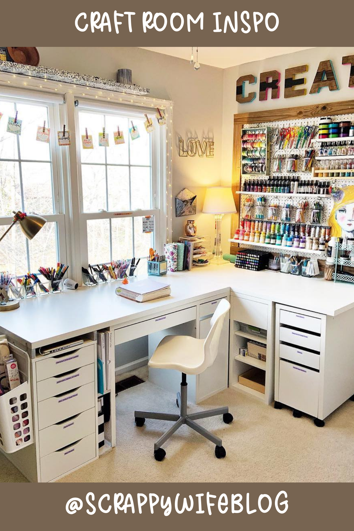 @scrappywifeblog – Talk about bright and inspiring! This room has it all: a spacious L-shaped desk with drawers for days and a wall filled with craft supplies perfectly arranged. The fairy lights and window add that magical touch, making it a perfect creative corner.