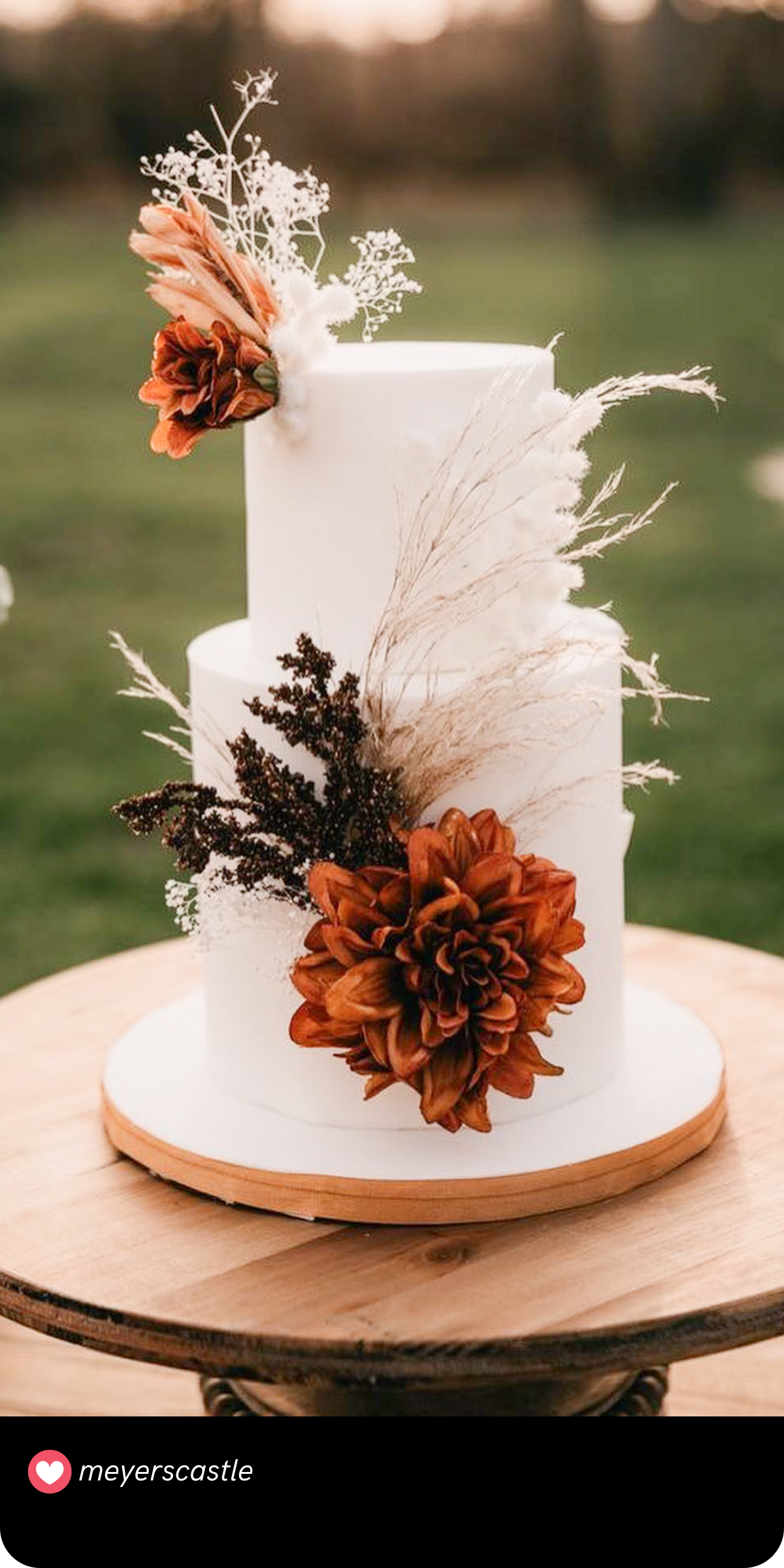 Rustic Fall Romance: This cake exudes rustic charm with its natural floral arrangements and warm autumnal colors, ideal for an outdoor fall wedding.