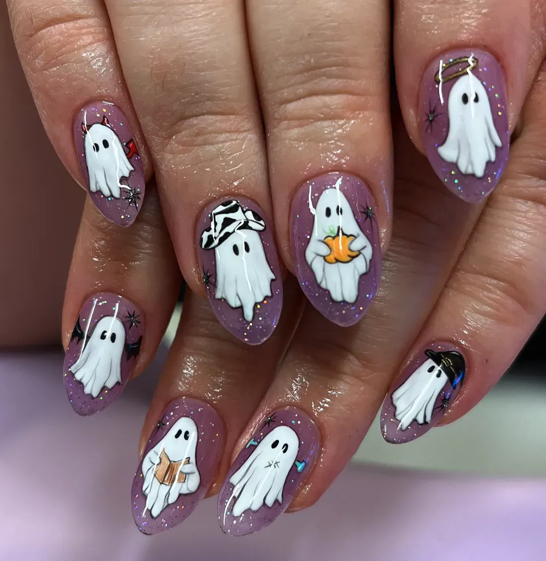 4. Dressed-Up Ghosts ✨Cowboy ghost? Check. Angel ghost? Check. Pumpkin ghost? Double check. This lilac nail set is packed with personality, each ghost showing off its own Halloween look. With sparkly backgrounds and tiny star details, this design is a whole ghost squad ready for spooky season selfies.