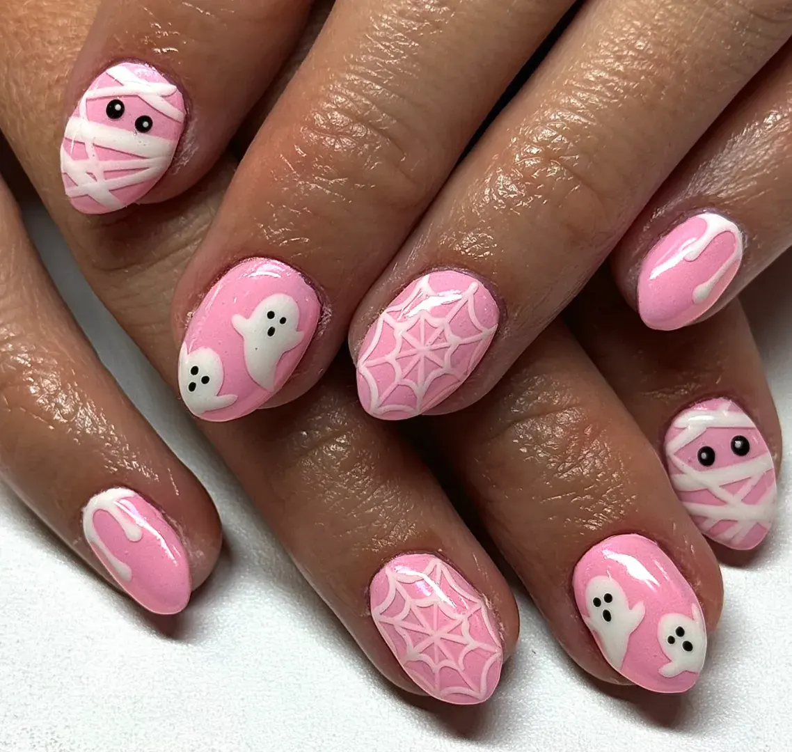 2. Bubblegum Pink Ghosts + Mummies 🎀If pastel spooky vibes are your jam, this ghost nail art is pure inspo. Soft pink nails become a playful canvas for mini mummies, spiderwebs, drips, and friendly little ghosts. It’s the ultimate mix of cute and creepy-cool, proving Halloween nails don’t always have to stick with black and orange.