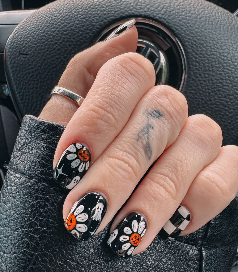 Spooky Florals – Black nails with daisy details, smiling pumpkins, and floating ghosts for a bold, artsy look.