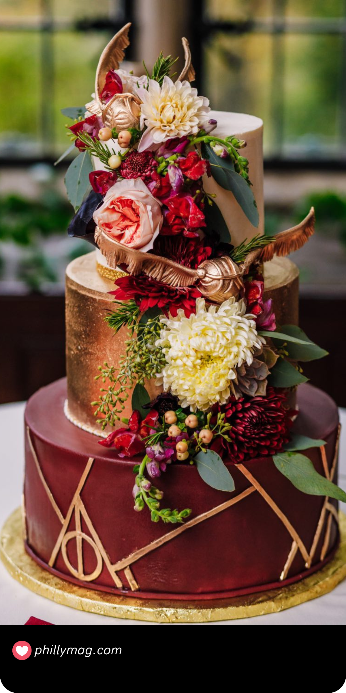 This stunning Harry Potter-themed wedding cake combines elegance with a touch of magic. The three-tiered design features rich burgundy and gold accents, with the bottom tier showcasing the iconic Deathly Hallows symbol. A cascading arrangement of vibrant flowers adds romance and charm, while the golden snitch nestled among the blooms brings a whimsical nod to the wizarding world. It’s the perfect blend of sophistication and enchantment for a truly magical wedding celebration.