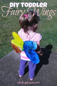 A toddler wearing a set of beautiful fairy wings that have been cut out from a cereal box and then painted on both side