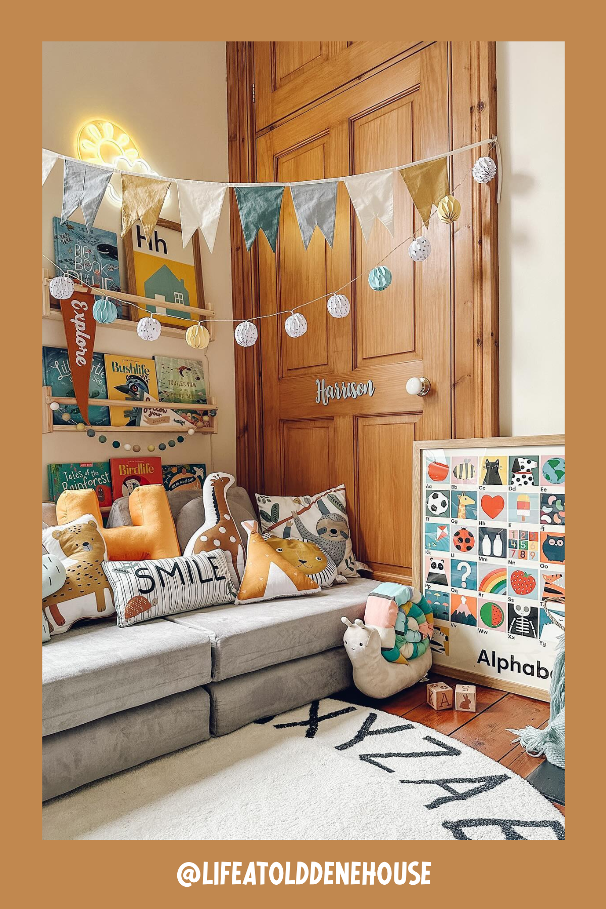 Brimming with warmth, this nook is packed with delightful details! Cushy gray seating is adorned with an array of whimsical animal and nature-themed pillows, while the wall is dressed up with garlands, banners, and a wooden name sign. Books neatly line the mini shelves, making this corner a lively, cheerful spot to explore new stories and spark little imaginations.