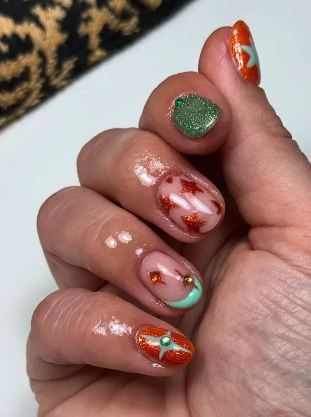 Tiny orange stars over soft teal and nude bases? It’s giving dreamy concert skies. Add rhinestones for a little extra sparkle. 🩵🧡 Nail art design inspired by Life of a Showgirl Taylor Swift 🩵🧡