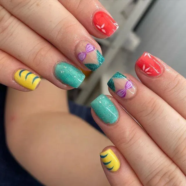 Bring under-the-sea vibes to your manicure with this colorful mix of teal, coral, and yellow. The tiny purple bows and shell details make it clear — this design is totally inspired by everyone’s favorite mermaid.