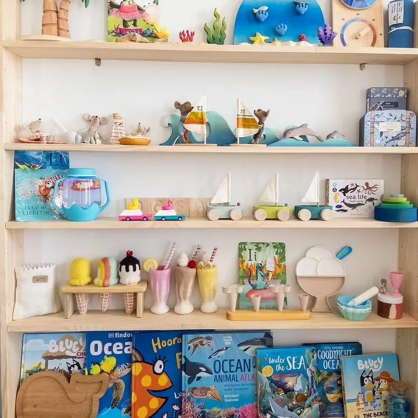 Ocean-Themed Bookshelf & Toy Display 🌊🐠A beautifully styled ocean-themed playroom shelf featuring wooden toys, beachy colors, and books arranged by theme. Perfect for fostering a love of reading and creative play!