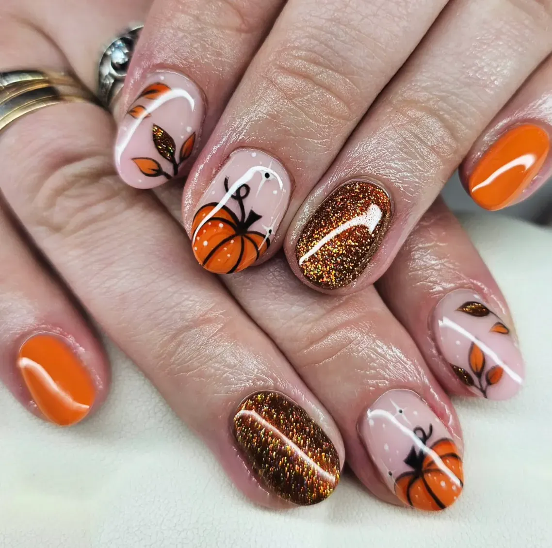 This design mixes glittery copper, bold orange, and cute pumpkin art. Think PSL energy but on your nails.