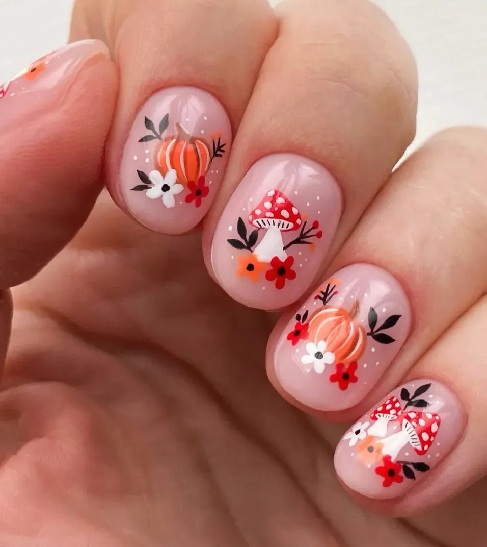 For a woodland twist, this design pairs tiny pumpkins with red toadstools and floral accents. It’s whimsical and cozy, like fall fairytale nails.