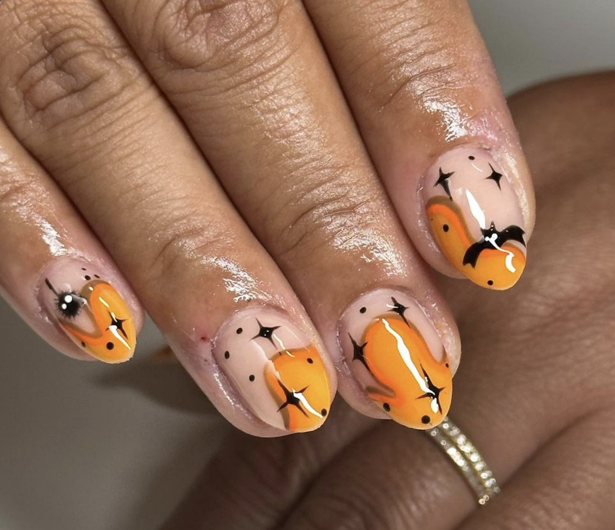 This Halloween nail design is giving all the retro vibes with a playful and spooky twist! The base is a soft nude shade, which really lets the bold, vibrant details pop. The standout feature is the swirling orange pattern that has a groovy, 70s feel—like candy corn with a modern twist! The orange waves are outlined with black, adding contrast and depth.