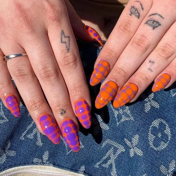 These nails showcase a vibrant and playful snake skin pattern, alternating between a bright orange base with purple scales and a purple base with orange scales. The glossy finish enhances the vivid colors, creating a bold and trendy look perfect for making a statement.