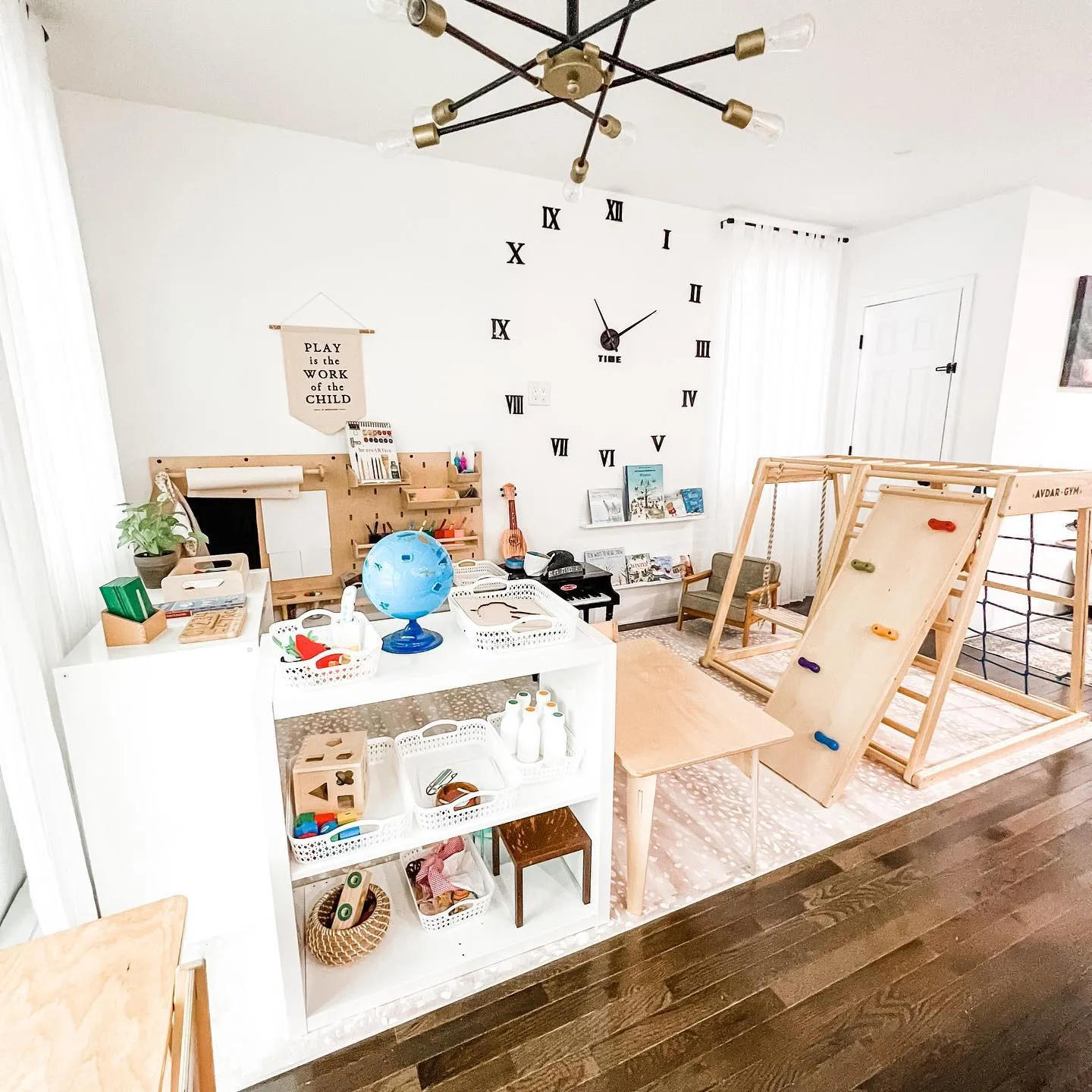 Montessori-Inspired Play Space – This minimalist yet engaging setup keeps things organized with labeled storage, a Pikler triangle, and a dedicated space for hands-on learning.