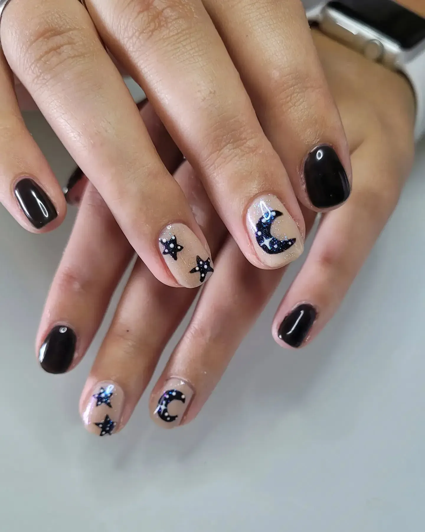 Simple yet enchanting, these short moon nails combine glossy black polish with tiny hand-painted stars for a minimalist take on witchy nail art. ๐คโญ