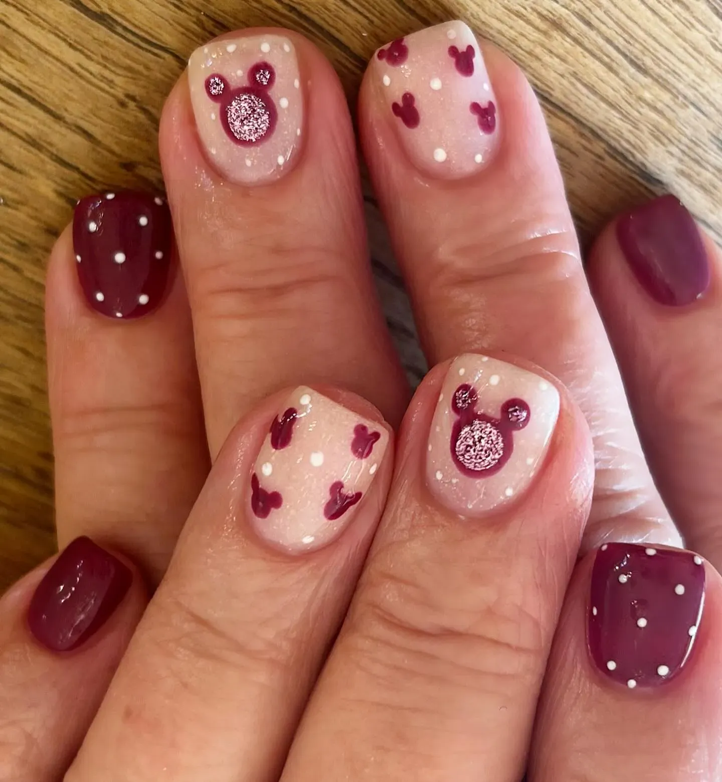 Rich plum polish paired with glittery Mickey heads and white dots — elegant enough for a dinner at Be Our Guest but still fun for the parks.