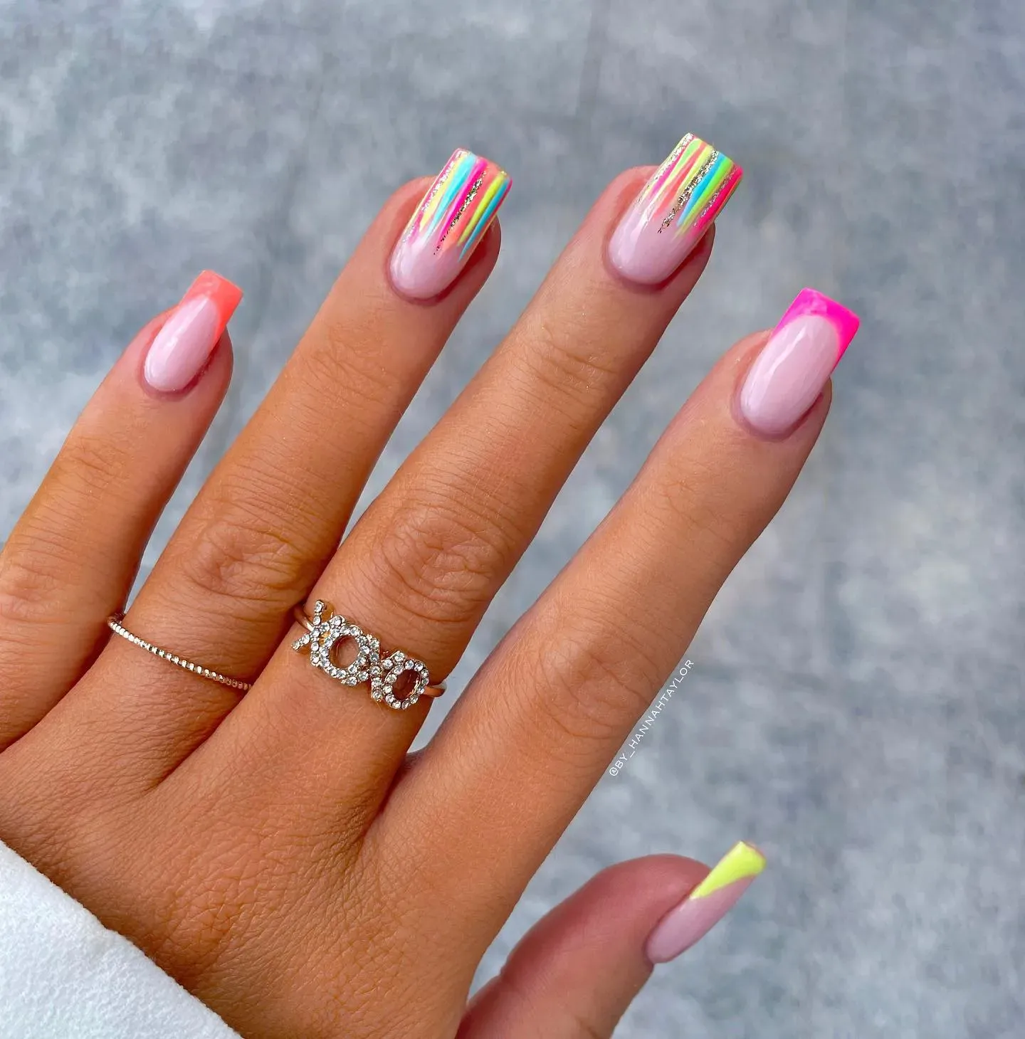 A soft pink base with fine rainbow lines and neon tips for a sleek, modern twist on the French manicure.