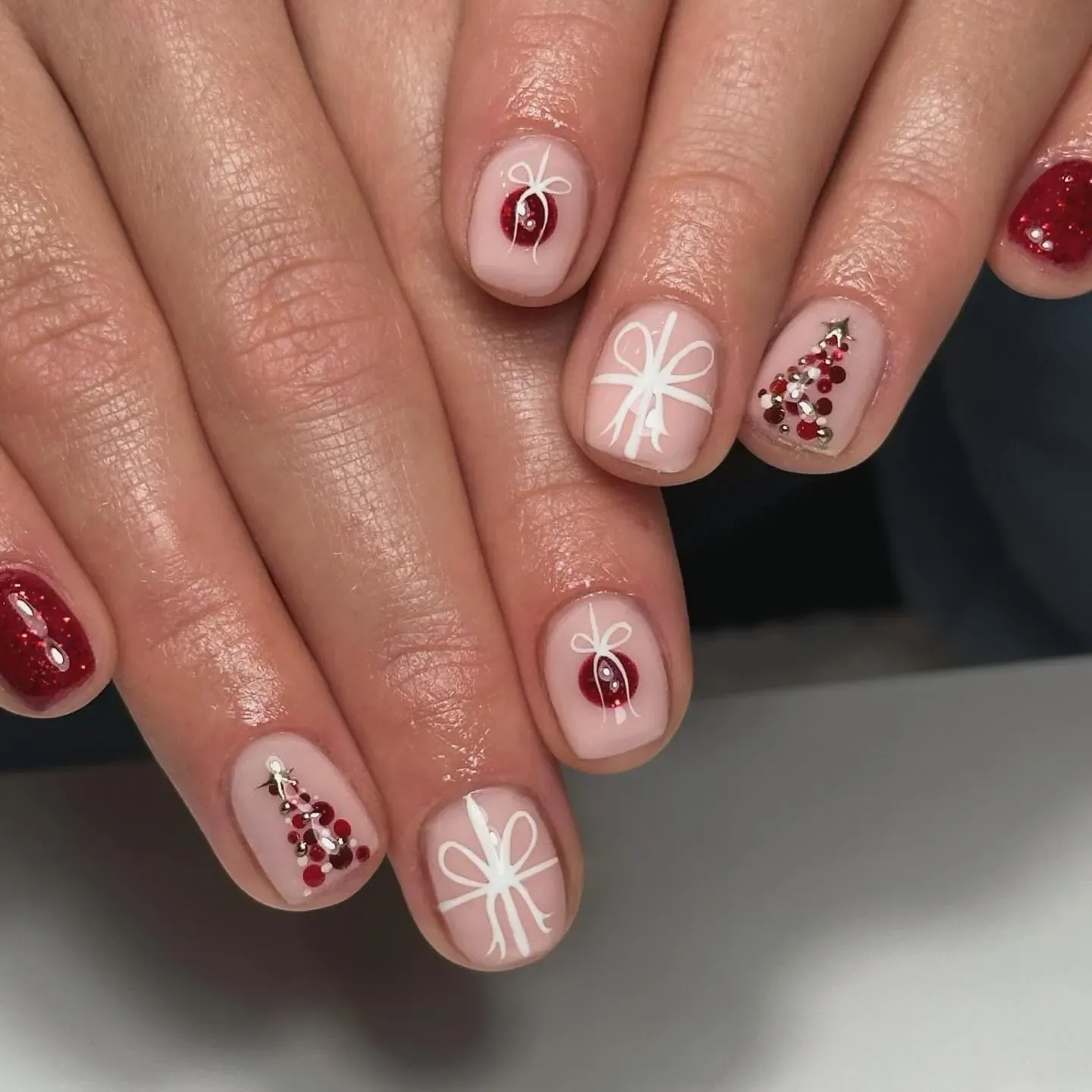 A sweet twist on subtle Christmas nails โ soft nude polish topped with mini bows, sparkling gems, and tiny Christmas trees for a delicate yet festive finish. ๐๐