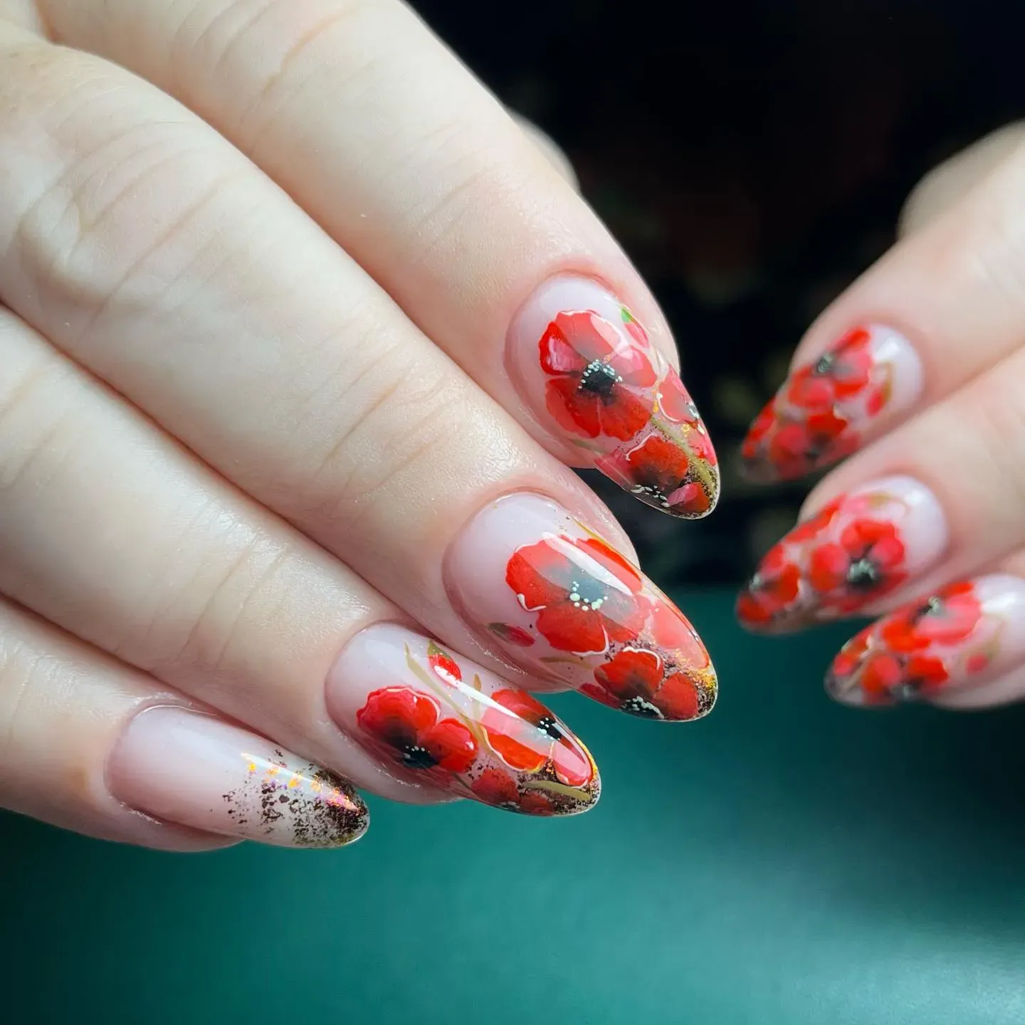 Bold and artistic, this poppy nail design by @colourcouturegel layers translucent nude tones with painted red poppies and a hint of shimmer. A perfect mix of statement and sentiment.