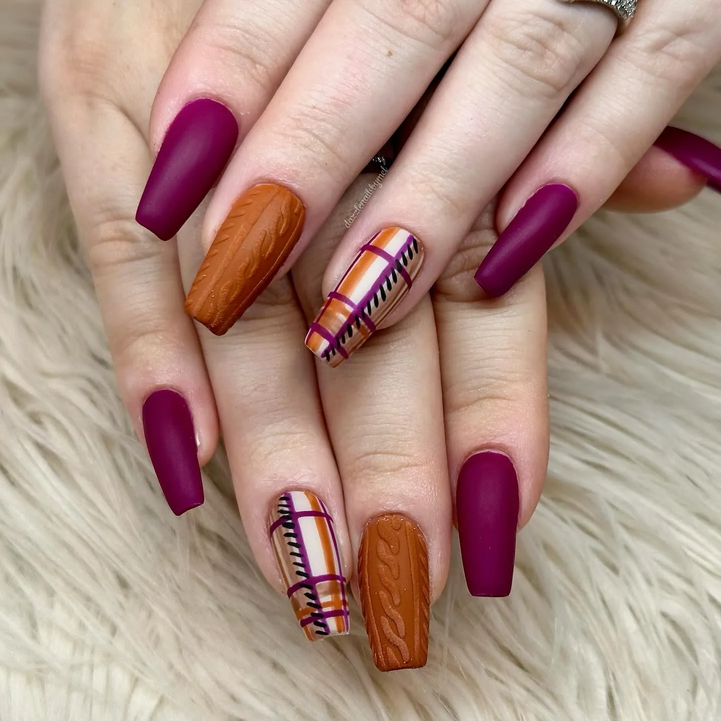 @dazzlenailsbymelMatte burgundy meets sweater-textured orange and plaid accents in this chic, layered look. These nails capture everything we love about fall — rich color, cozy texture, and serious Thanksgiving nails inspiration.