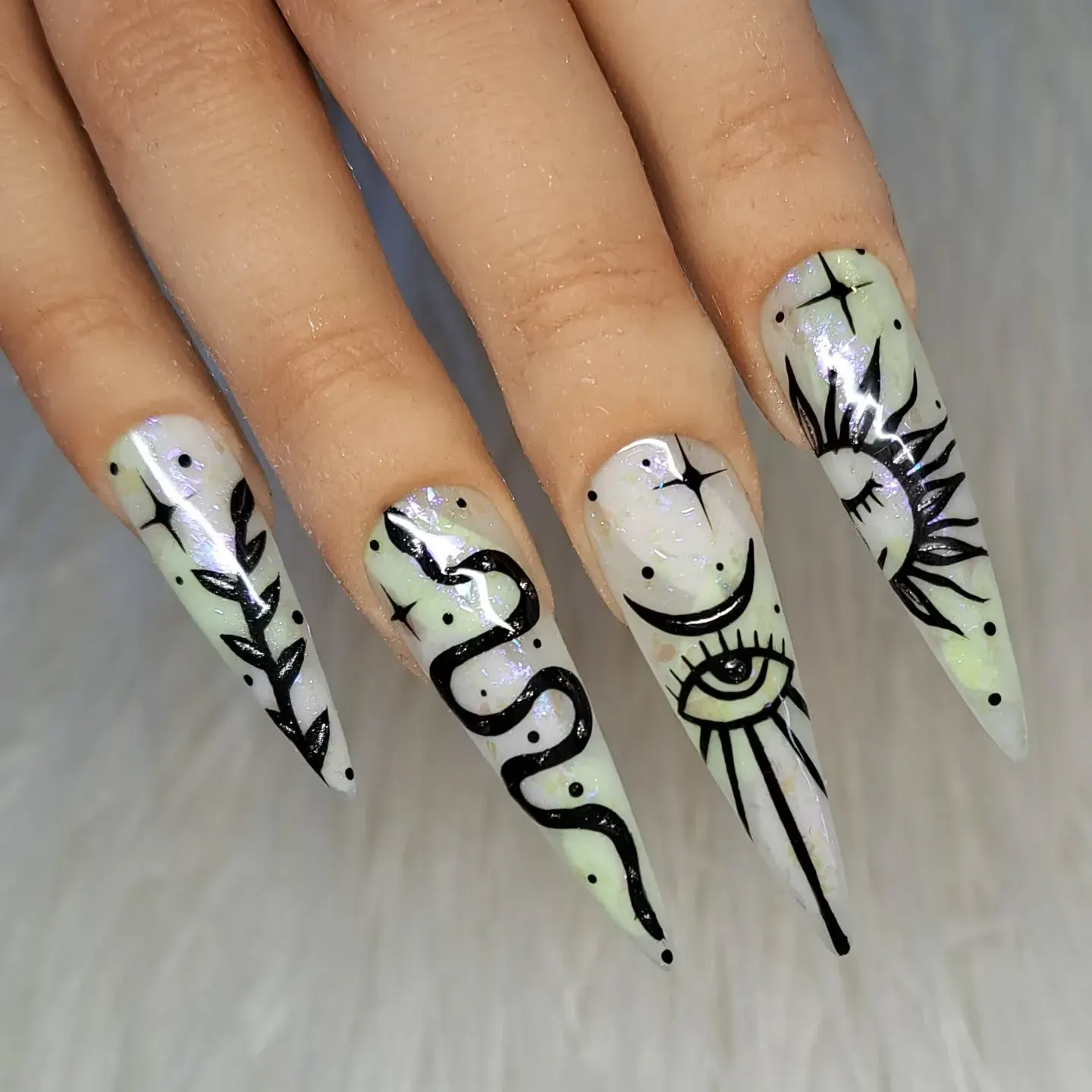 These ethereal witchy nails feature hand-painted black celestial symbols โ serpents, moons, and all-seeing eyes โ over a soft shimmer base. Perfect for anyone drawn to mystical nail designs that feel straight out of a spellbook. ๐โจ