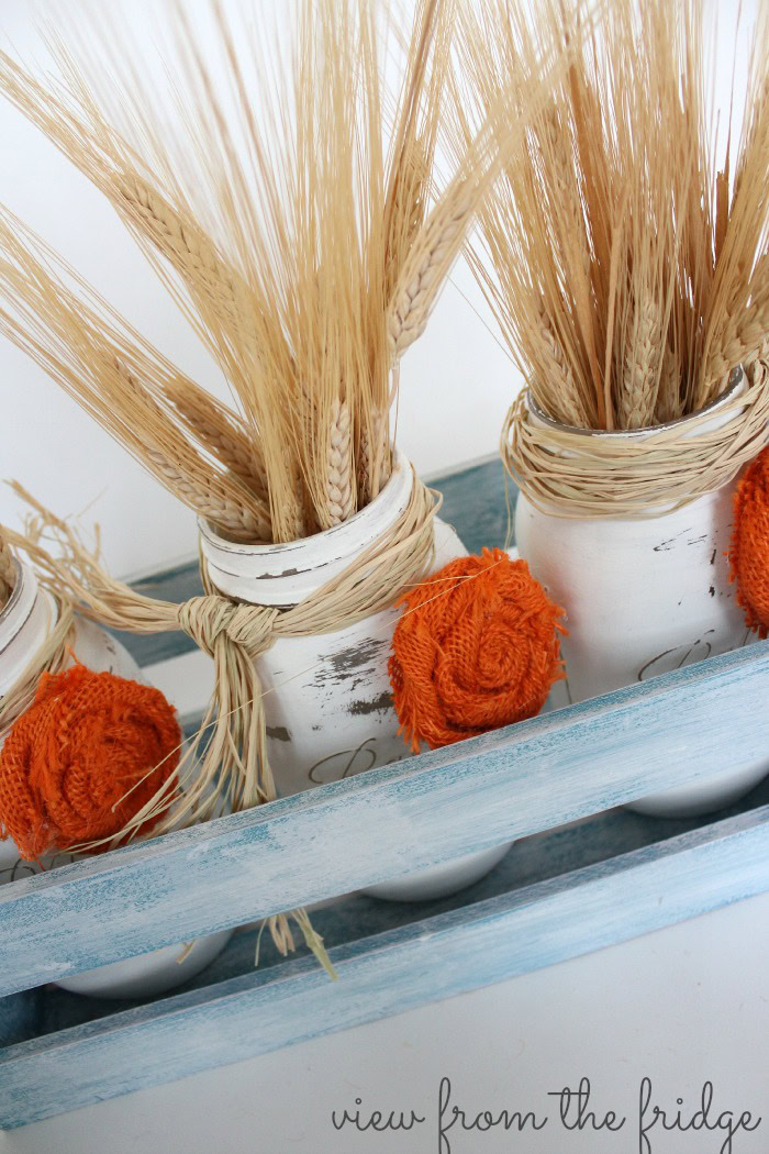 These Fall Easy Mason Jar Centerpieces are a perfect Fall decor accent for the home. Use it to decorate the table, fireplace mantel or as fall front porch decor! The distressed mason jars are accented with easy to make burlap rosettes! OHMY-CREATIVE.COM