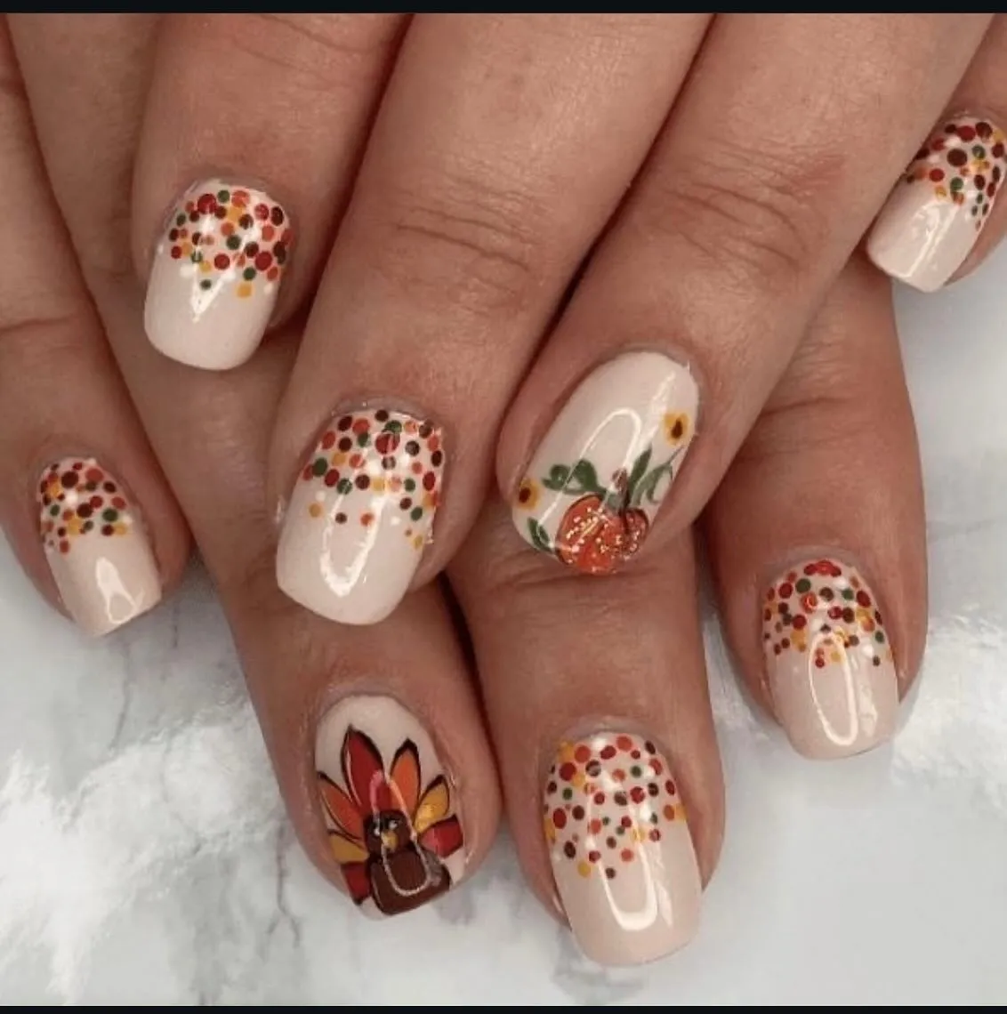 6. @hanrahan79Soft neutrals and tiny dots create the prettiest base for cute turkey and pumpkin accents. This look proves Thanksgiving nails can be festive without being over the top — perfect for anyone who loves simple fall nails.