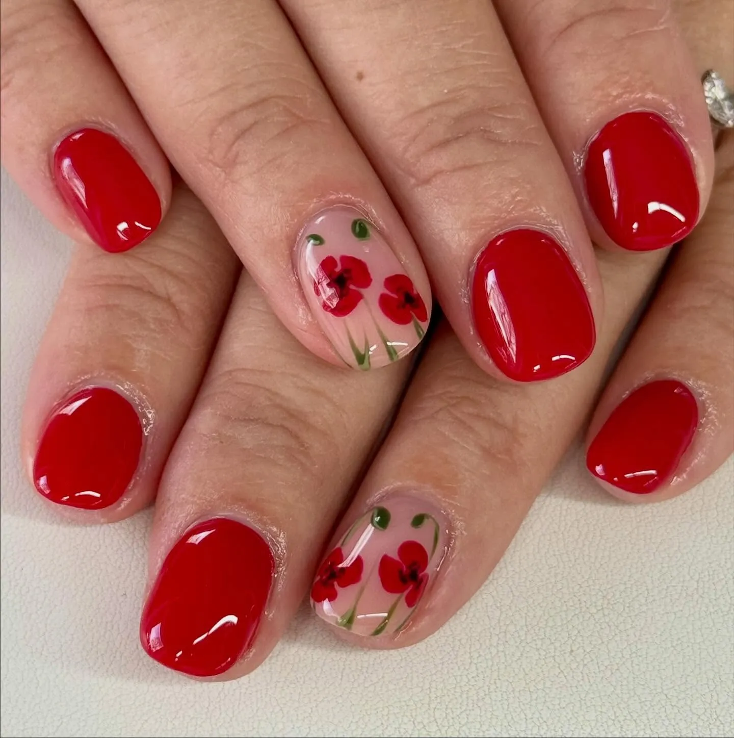 Glossy red meets translucent floral art in this beautiful remembrance set by @louise_greaves_nail_artist. It’s a lovely balance of bright, confident color with a deeper message behind it.