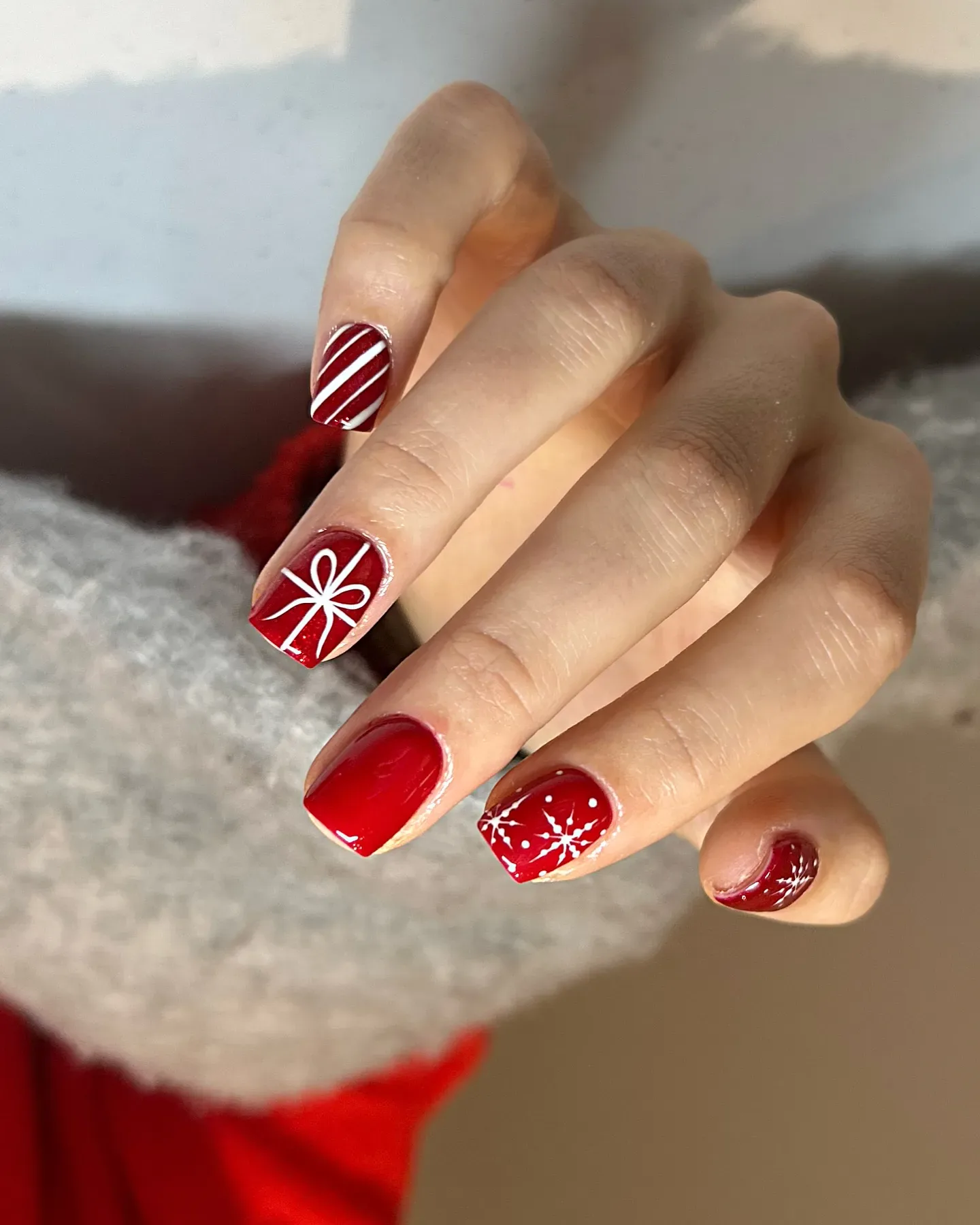 Classic red nails get a festive twist with candy-stripe accents, delicate bows, and snowflakes โ simple, classy, and perfect for short Christmas nails. ๐โจ